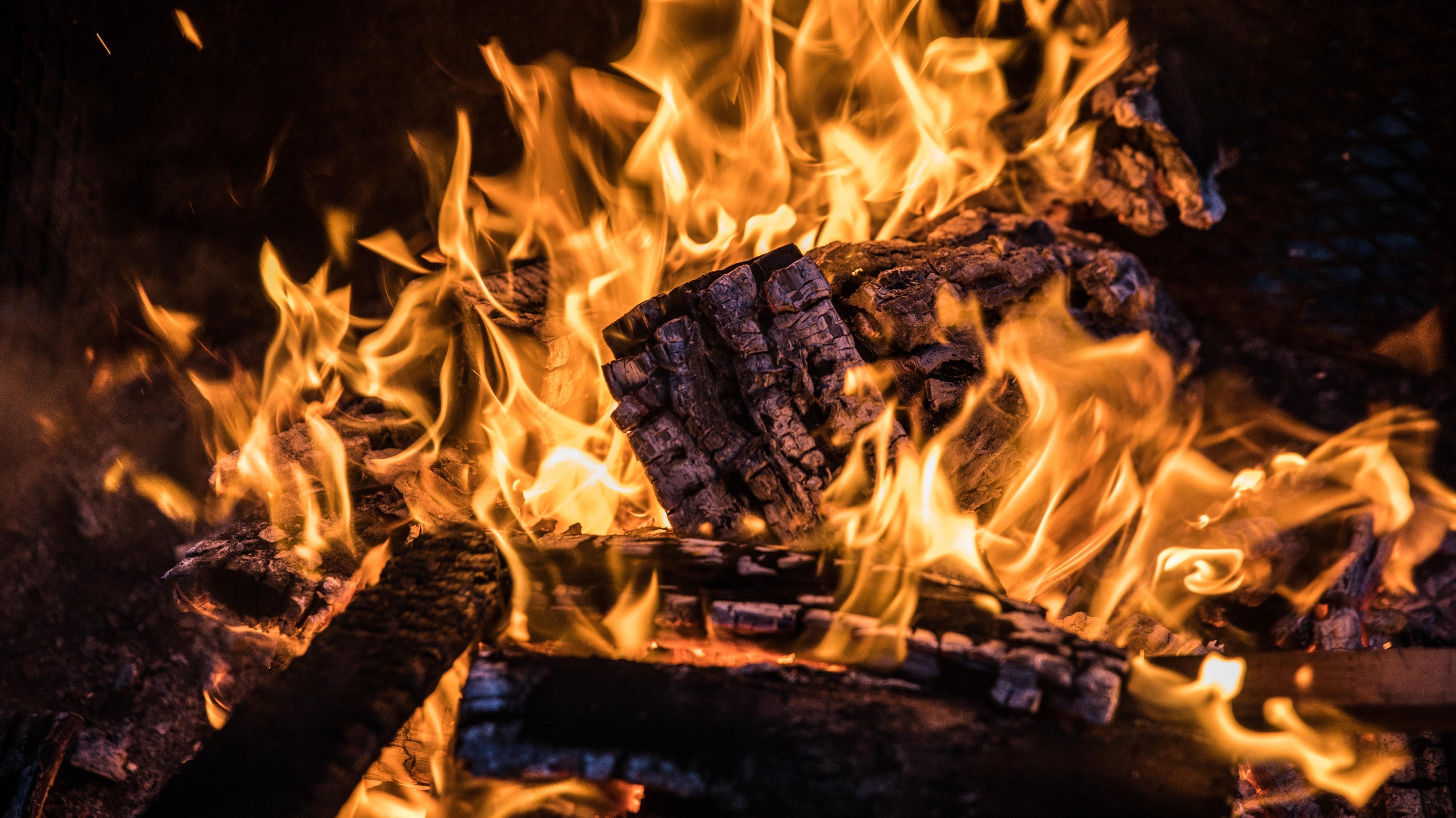 Closeup of burning firewood with bright orange flames in a campfire setting
