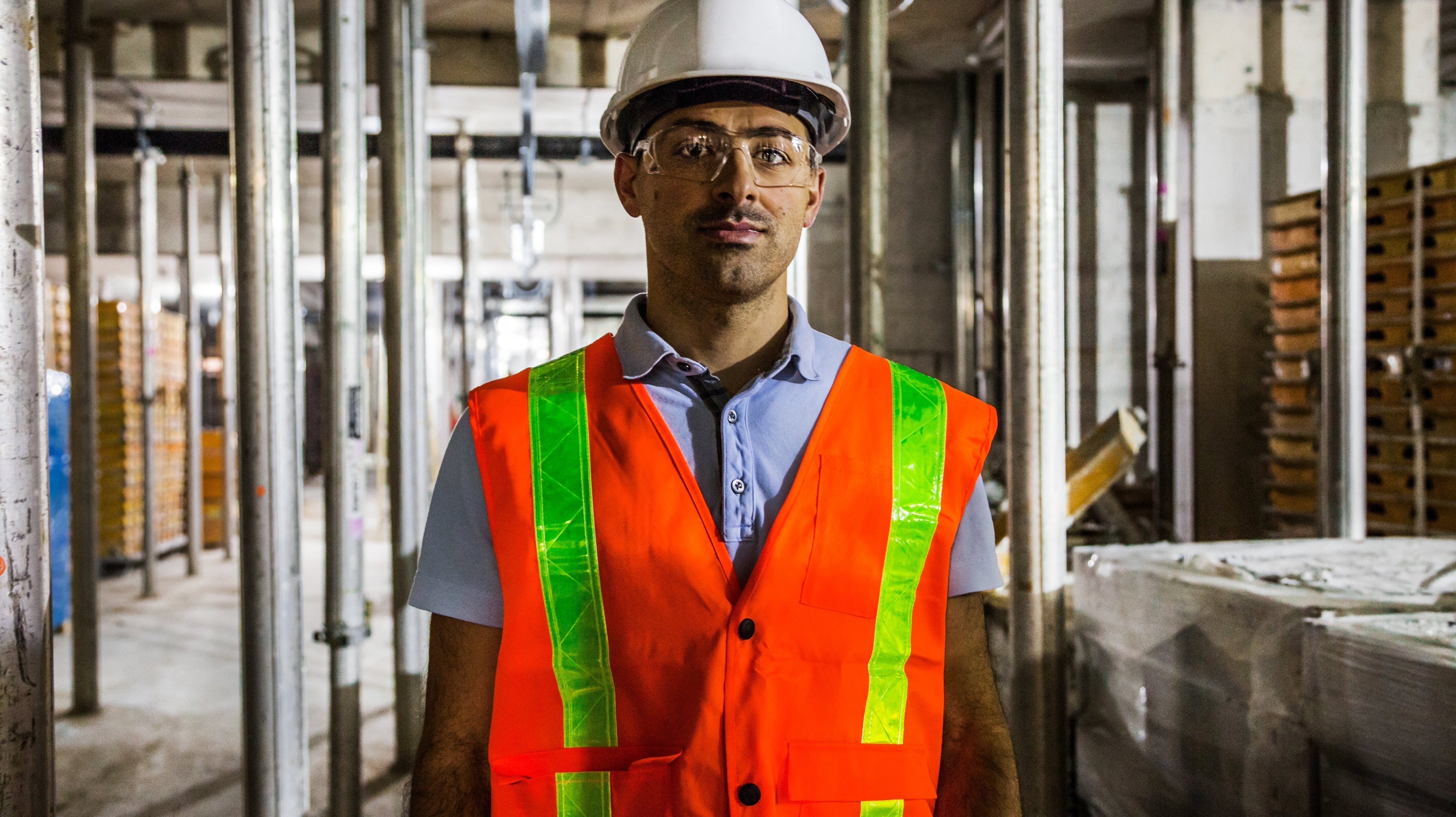 Construction worker in safety vest, hard hat, and goggles at building site