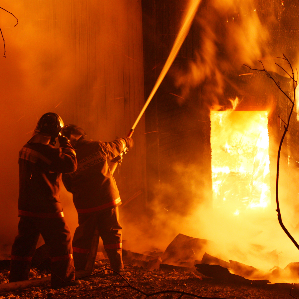 Firefighters extinguishing an intense house fire through a doorway, fire protection concept