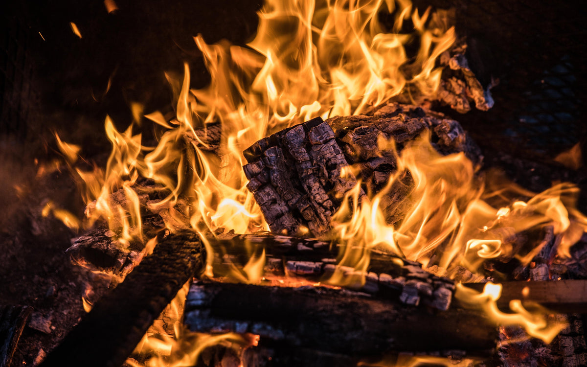 Closeup of burning firewood with bright orange flames in a campfire setting