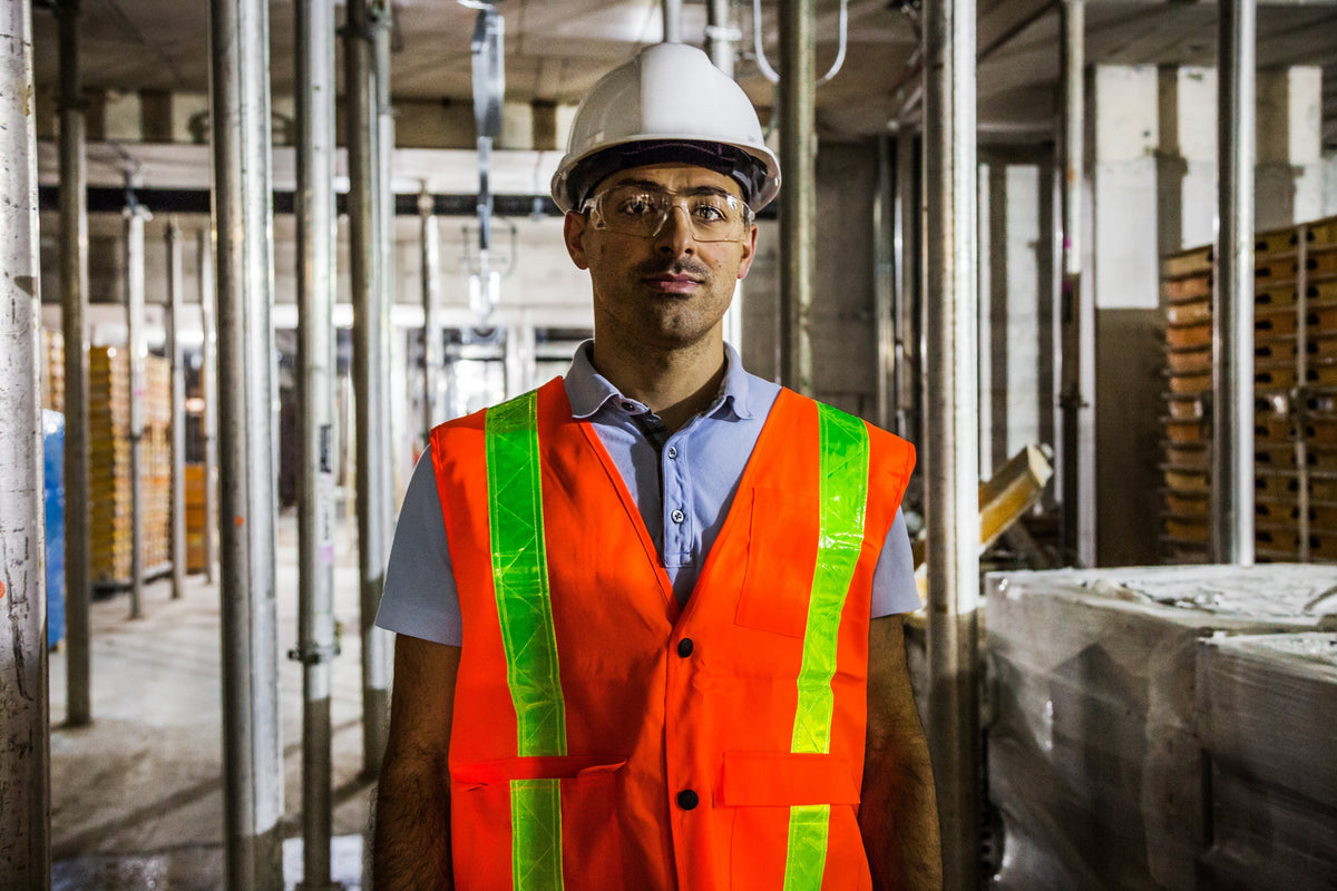 Construction worker in safety vest, hard hat, and goggles at building site