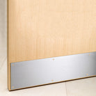 Oak fire door with brushed metal kick plate installed at bottom, on tiled floor