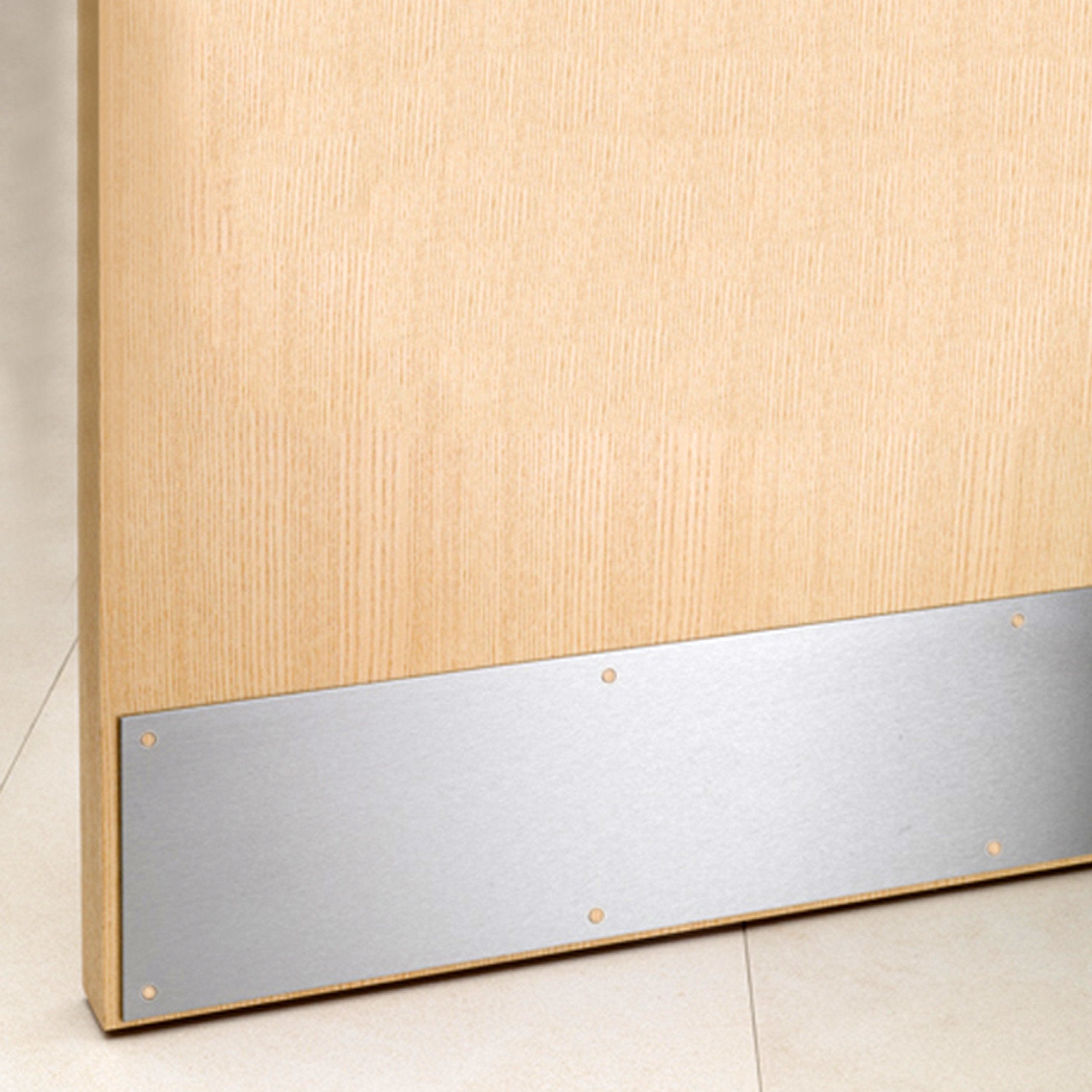 Oak fire door with brushed metal kick plate installed at bottom, on tiled floor